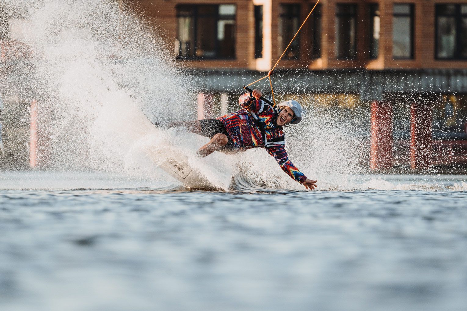 Wakeboarder schneidet durch das Wasser und erzeugt eine große Spray-Wand