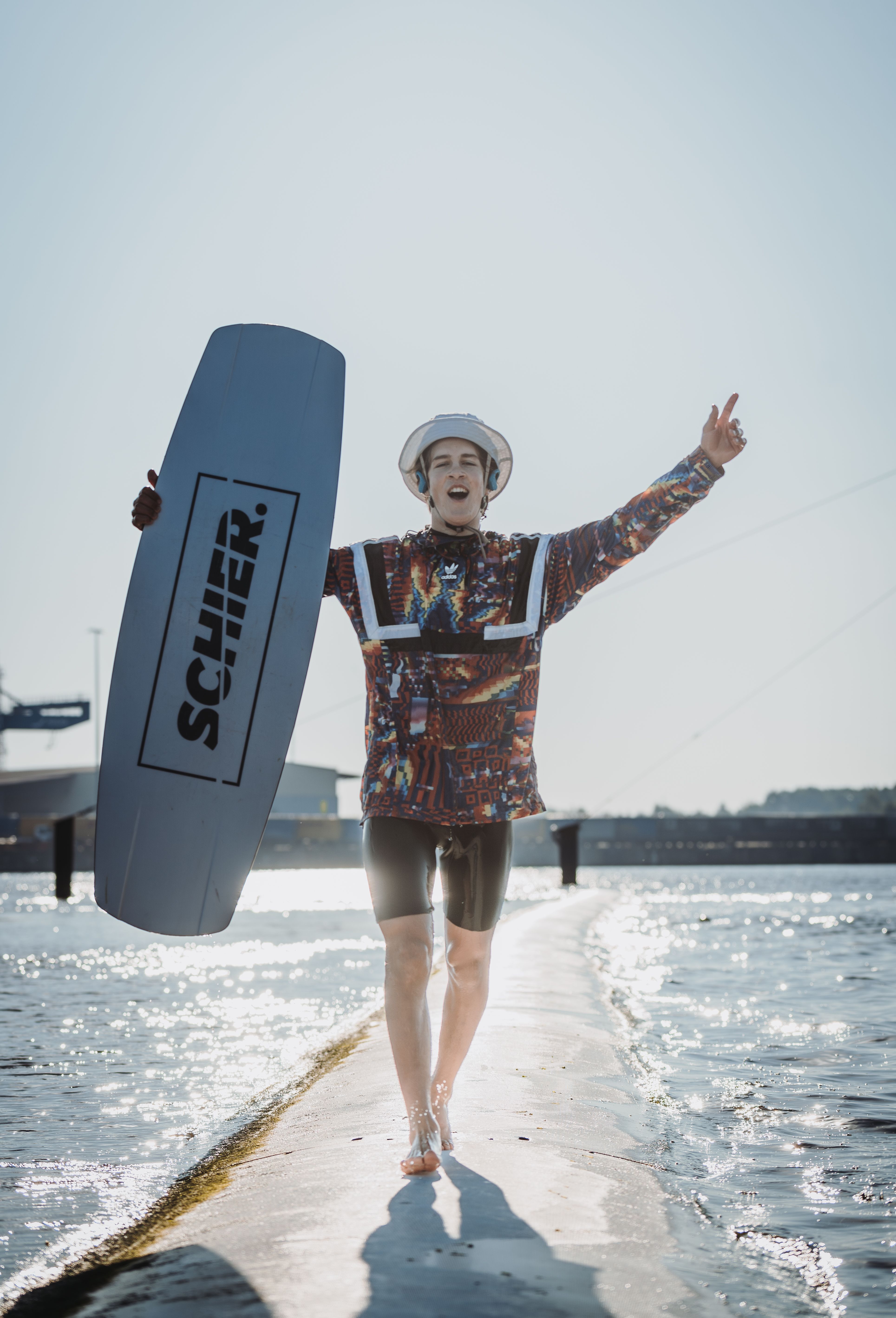 Wakeboarder läuft am Wasser entlang